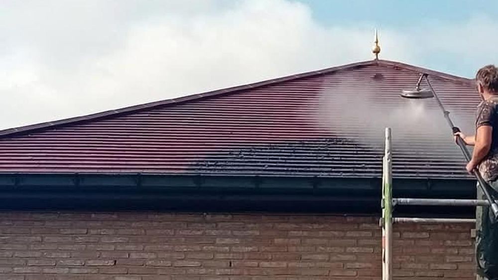 Dak wordt ontmost, het gereinigde deel is duidelijk zichtbaar