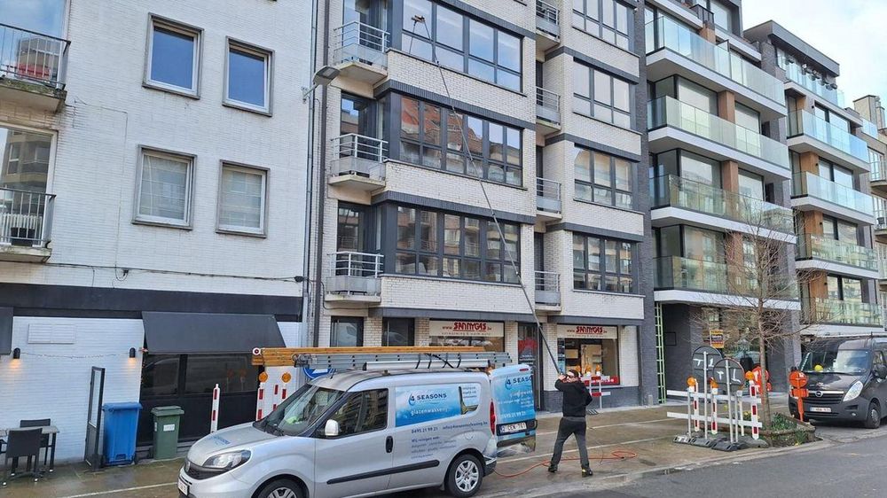 Ruitenwasser van 4 Seasons aan het werk met telescoopstok in een winkelstraat